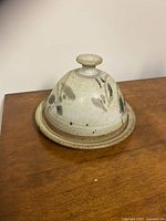 Closed view of the pottery butter dish showing dome-shaped lid with knob handle and leaf decorations.