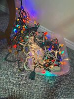 Photo of assorted Christmas light strings tangled in clear plastic bin showing multi-colored and white wire light strands.