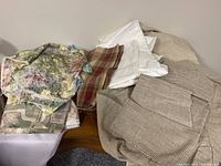 Image showing assorted stack of fabric including beige, plaid, and floral print pieces on a table surface.