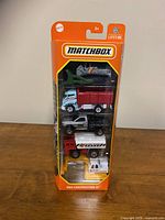 Front view of sealed Matchbox MBX Construction III series pack showing all five new construction vehicle toys upright in blister packaging on an orange card.