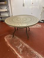 Top view of the round metal patio table showing the perforated pattern on the tabletop.
