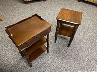 Two wooden side tables together on carpeted floor, one rectangular with drawer, one square without drawer.