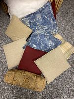 Overview of assorted throw pillows in various colors and sizes arranged on carpet.