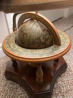 Close-up of the vintage zodiac globe on a wooden base showing celestial and zodiac signs and detailed aged patina
