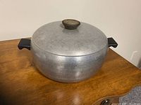 Side view of the vintage Wear-Ever aluminum soup pot with lid on wooden surface.