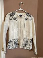 White long sleeve YakMagik top with black floral and abstract patterns on front and sleeves on hanger.