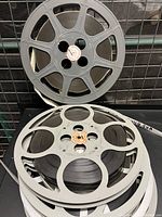 Four metal film reels stacked, showing reel design and film wound around reels.