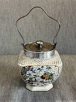 Front view showing the floral pattern on one side of the biscuit tin and the metal lid with handle attached