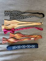 Photo showing five assorted ties: two bow ties and three neckties in various colors and patterns.