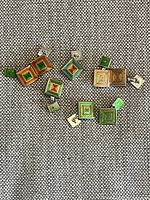 Four pairs of cufflinks arranged on fabric, showing orange and green enamel concentric square patterns.