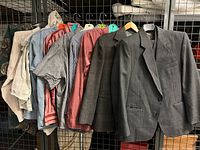 Image showing 6 shirts and 3 suits hanging on hangers against a metal grid background.