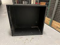 Front view of black metal firebox insert showing hollow interior and lip around edges.