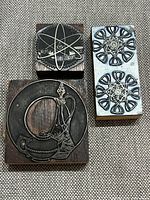 Three metal print blocks mounted on wood, showing detailed illustrations and patterns