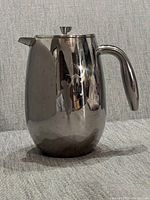 Stainless steel French press coffee maker side view showing etched child holding toy plane design.