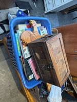 Top view of blue plastic basket showing wooden box, turkey decoration, books and other wooden items inside