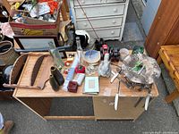 Shot of a table filled with assorted decor items including glassware, wooden rack, metal vases, figurines, and trays