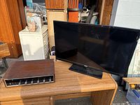 LG flat-screen TV and vintage wood-cased audio receiver pictured on a wooden desk.