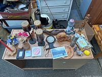 Table filled with assorted candles, knickknacks, mini lantern, magnifying glass, and small figurines spread out in a random display