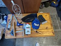 Top-down image showing an assortment of household and garden tools and items arranged on a wooden chest.