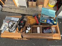 Electric sanders, wooden tool box with hand tools and accessories on wooden surface