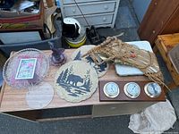 Top down view of assorted decorative wall hangings and plates arranged on a table outdoors.