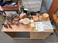 Overhead view of a table with various vintage decor items including wooden bowls, ceramic jug, metal pots, candles, framed photo, and small decorative objects.