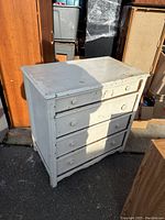 Full front view of the vintage white wooden dresser with four drawers showing chipping paint and wear.