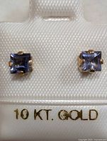 Front view of pair of square-cut iolite 10K gold earrings in white display holder marked 10 KT. GOLD.