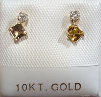 Photo showing front view of two earrings each with a small round diamond and a colored tourmaline stone in 10K gold setting on seller display card.