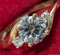 Close-up front view of ring showing center and side stones on red fabric