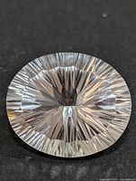 Top view of the oval white topaz gemstone highlighting the intricate starburst faceting pattern and clarity.