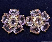 Close-up of pair of flower-shaped earrings with seven oval faceted amethyst stones around white topaz cluster.