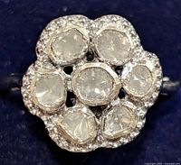 Close-up photo of the front face showing seven rose-cut diamonds arranged in floral cluster, surrounded by small accent diamonds with silver setting.