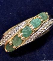 Close-up front view of the silver emerald ring showing the five oval emeralds and clear stone accents.