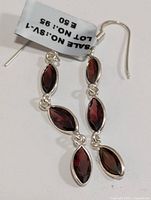 Pair of silver earrings with marquise garnet stones front view with price tag showing lot and sale numbers.