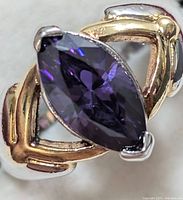 Close-up front view of silver ring showing marquise-cut deep purple gemstone with polished silver and gold-toned band design.
