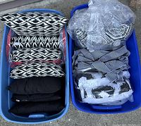 Two bins filled with various black and white decorative pillows, some in plastic bags