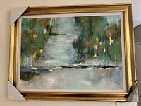 Full view of the large framed hand-painted artwork showing abstract landscape with green, blue, yellow hues and gold frame corners protected by cardboard.