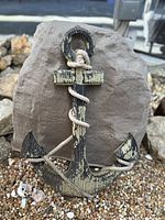 Large wooden anchor with distressed black and beige paint and natural rope coiled around