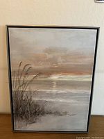 Full view of framed oil painting showing coastal sunset scene with ocean waves and marshy grass foreground.
