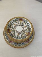 Stacked view of two Royal Worcester porcelain plates showing detailed colorful floral and scroll patterns with gold trim.