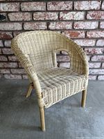Front-side view of small vintage wicker chair showing woven construction and curved armrest.