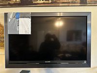 Front view of the Sony 40-inch TV showing the screen and frame with the manual taped at the top left corner.