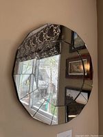 Angle view of the round segmented glass wall mirror reflecting a window and wall decor.