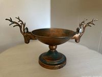 Front and side view showing the bowl's patina finish and deer head antler handles