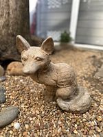 Front side view of vintage sitting fox statue showing detailed facial features including eyes, nose, and large ears, with textured cement surface.