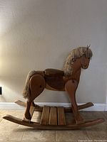 Side view of wooden rocking horse showing full body, rockers, and footrest.