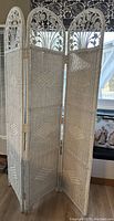 Photo of three-panel wicker room divider with carved wooden arch tops showing the design and condition.