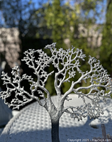 Aluminum metal tree sculpture with detailed branching, shown in natural lighting highlighting texture and form.