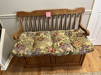 Front view of oak wooden bench with floral cushioned seat and visible storage compartment base.